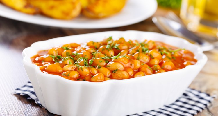 Crock-pot baked beans in a white serving dish on a table