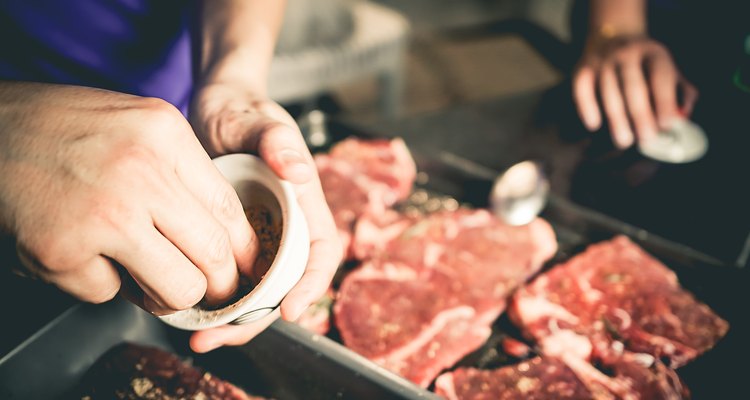 Human hand is preparing BBQ steak for party.