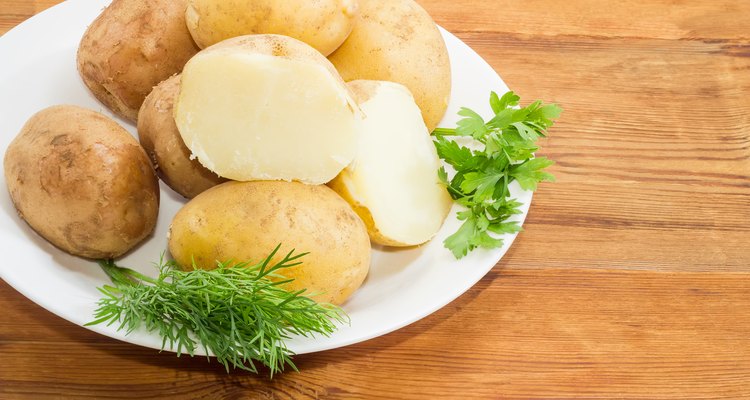 Potatoes boiled in their skins and herbs on dish closeup