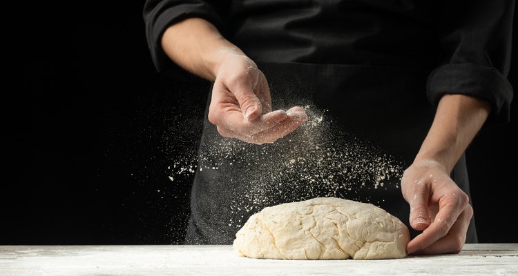 Cook baker prepares bread, focaccia, pizza, buns, sweets. Horizontal photo. Bakery concept, cooking flour products. Design for text.