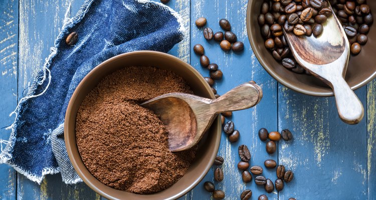 Bowls of uncut and ground coffee beans on blue wooden table