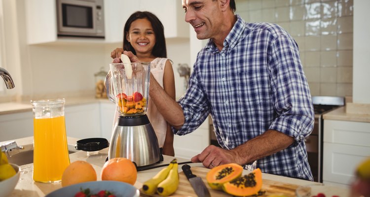 Father and daughter preparing smoothie in kitchen