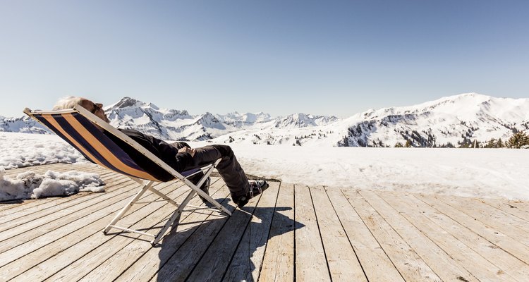 Austria, Damuels, senior man relaxing in deckchair on sun deck in winter landscape