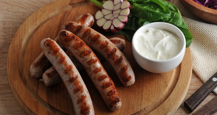 grilled bratwurst sausages with sauce, spinach and garlic