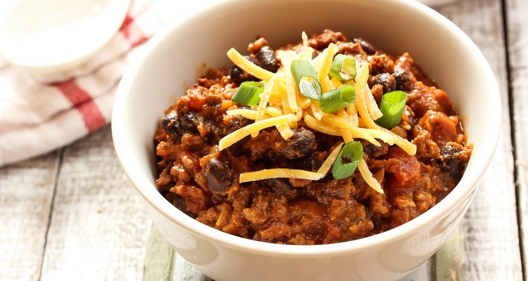 Beef chili with beans and cheese topping in a bowl on a table