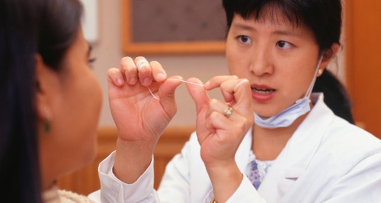 Una dentista demostrando el uso adecuado del hilo dental.