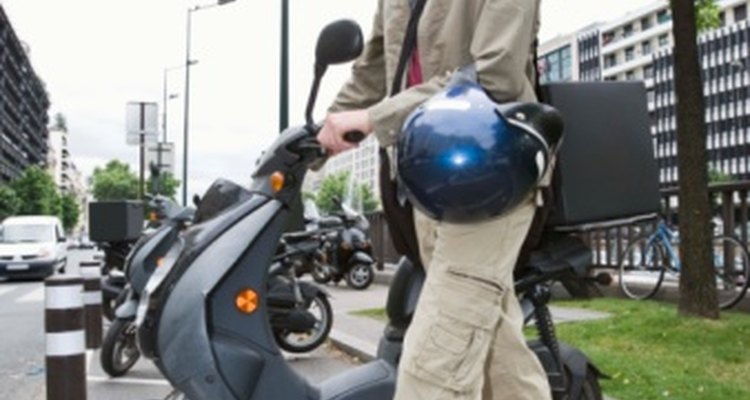 A man rides to ride a scooter.