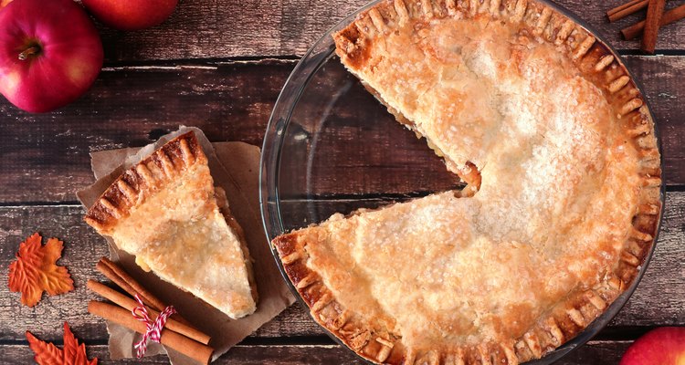 Apple pie with cut slice on rustic wood