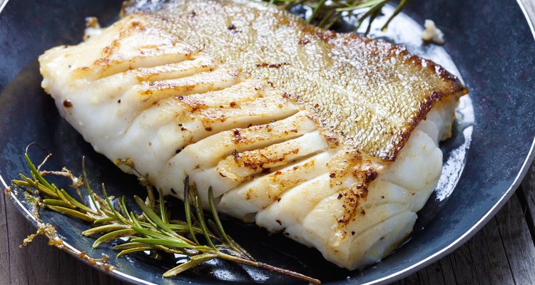 Close-up of a cod fillet with rosemary on a plate