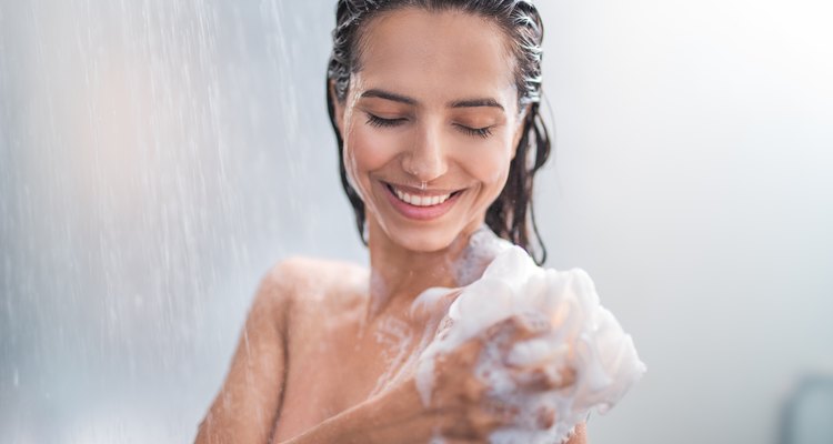 Smiling female rubbing body with foam