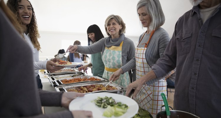 Happy senior women serving food at soup kitchen community dinner