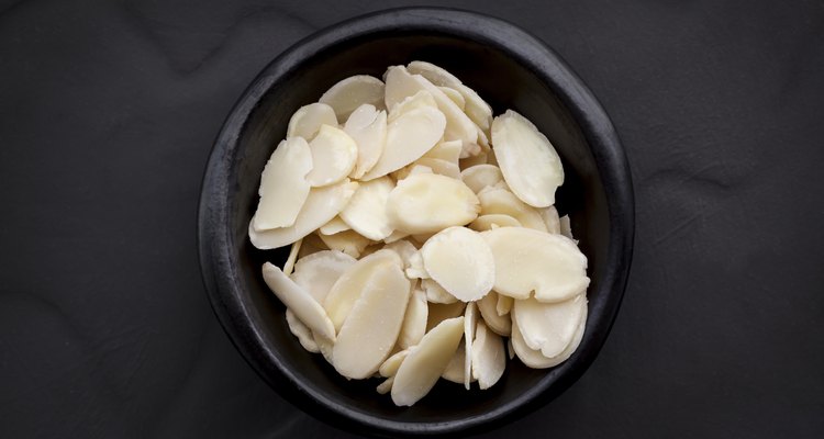 Almond Flakes in Black Bowl over Dark Slate Overhead View.