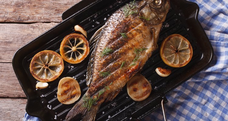 Grilled fish with lemon in pan , horizontal top view closeup