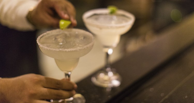 Closeup of an unrecognizable Panamanian bartender putting the final touch on a margarita cocktail by placing a lime wedge on the glass rim