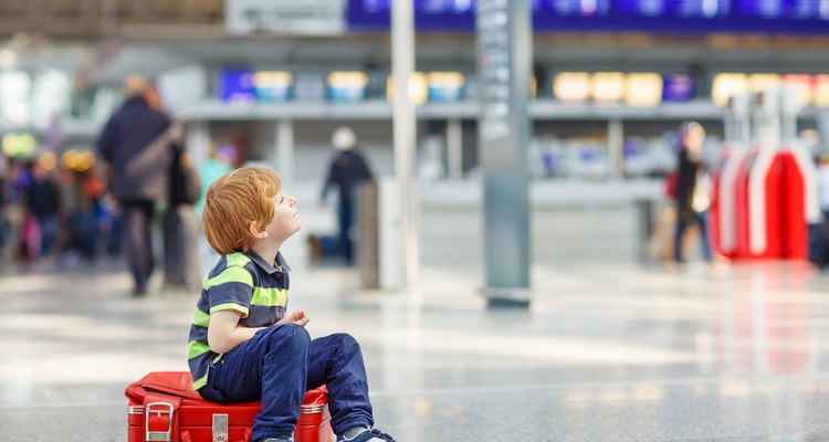 Little boy sitting on a suitcase at the airport