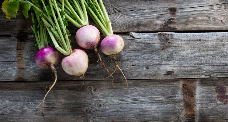 imperfect organic turnips, fresh green tops on authentic wood background