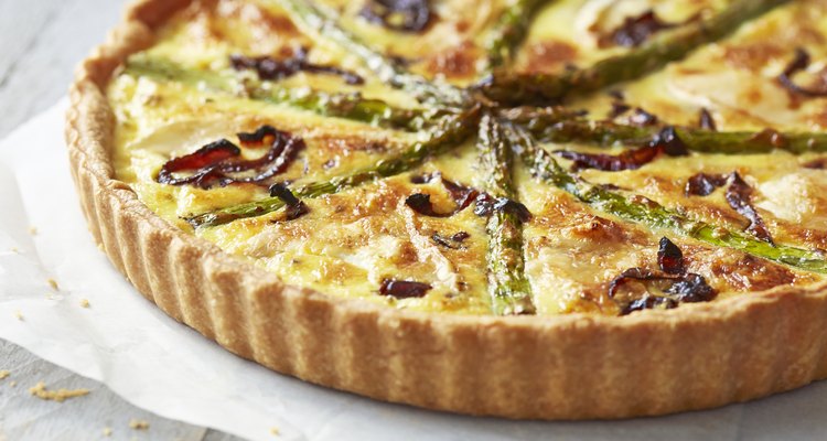 Asparagus quiche on white wooden surface