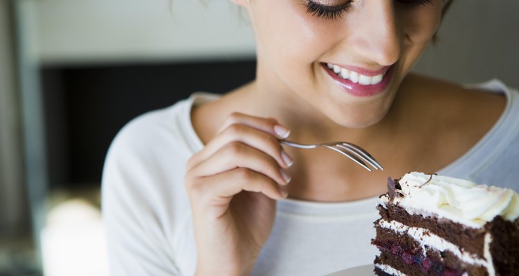 Smiling woman eating chocolate cake with a fork