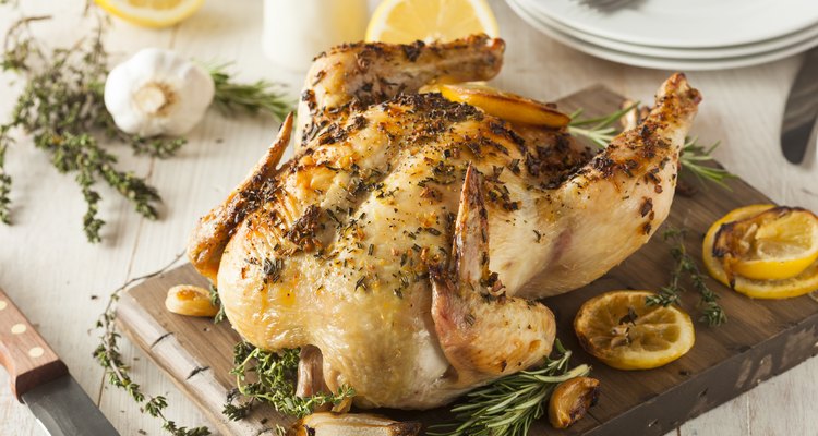 Lemon and herb whole chicken on wooden board