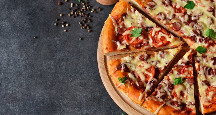 Home pizza with salami, tomato and cheese on a black background