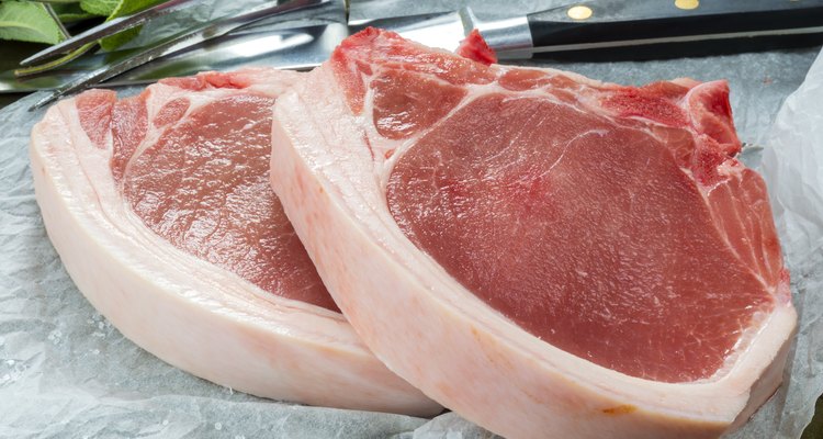 Two raw pork chops arranged for prep cooking