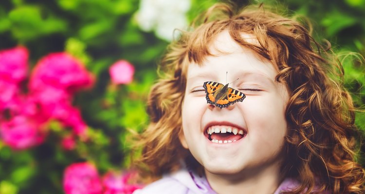 Laughing little girl with a butterfly on her nose