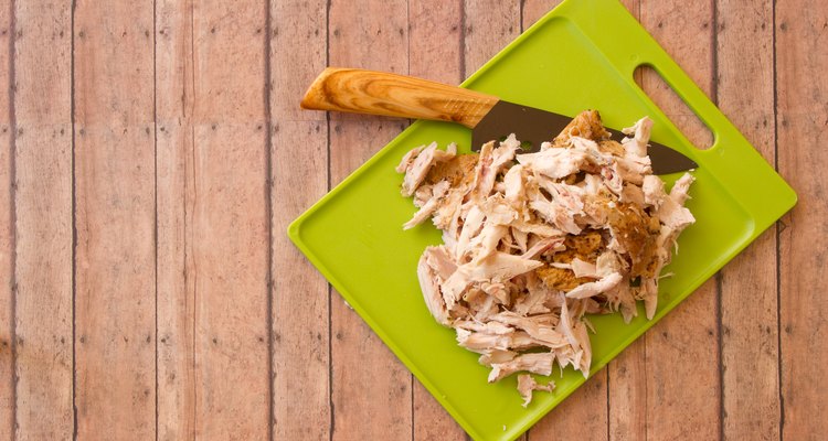 Shredded chicken on a cutting board with a knife