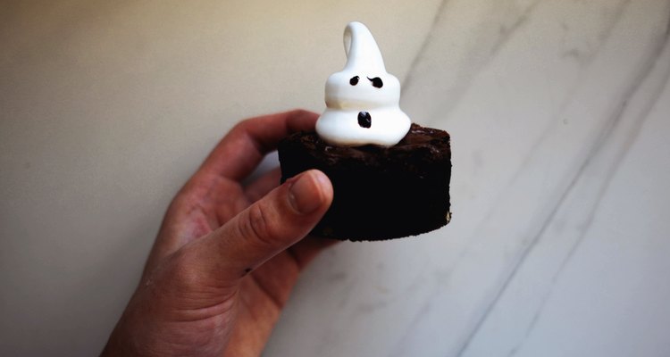 Use the melted chocolate to form faces on the ghost brownies.