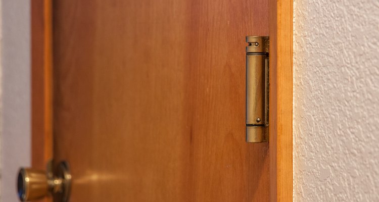 A dobradiça de porta com mola fornece tensão para fechar a porta