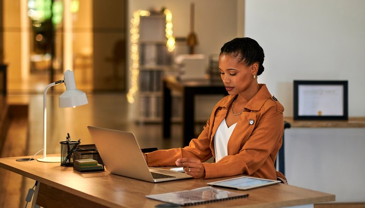 Mujer sentada frente a computadora portátil realizando una búsqueda en línea.