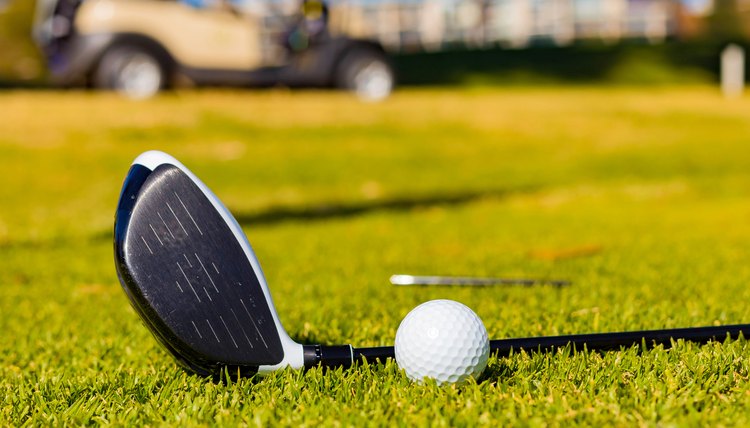 Shallow focus of a golf club and a ball on a lawn