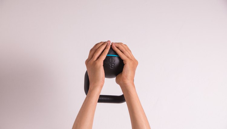 Midsection Of Man Holding Kettlebell Against White Background