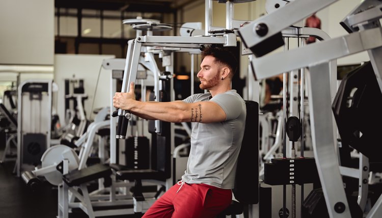 mid adult man in gym sitting on bench, working out with weights