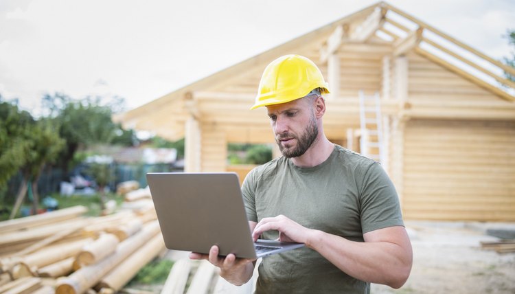 Hombre en sitio de construcción con laptop.