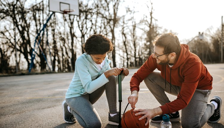 Father with daughter inflating basketball with pump