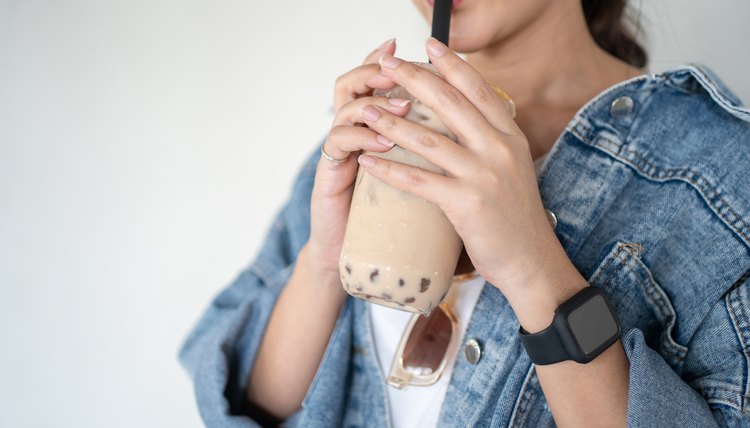 Mujer con vestimenta casual bebe té de burbujas helado.