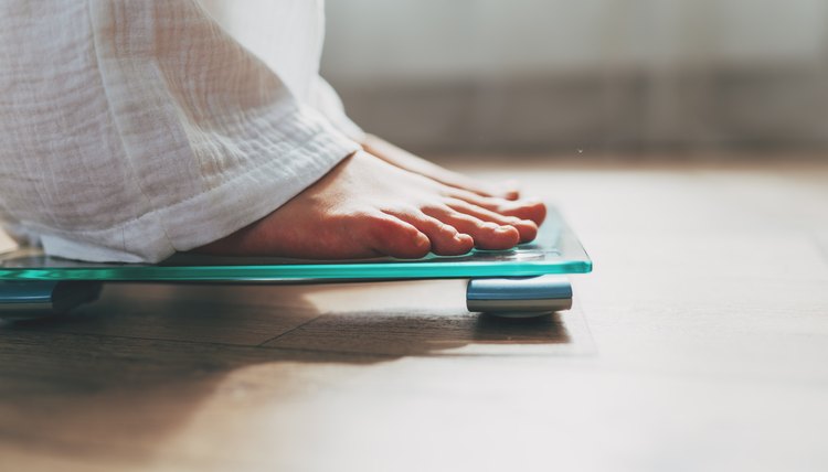 Top view of feet on weighing scale. Women weigh on a weight balance scale  after diet control. Healthy body weight. Weight and fat loss concept. Weight  measure machine. Body Mass Index or