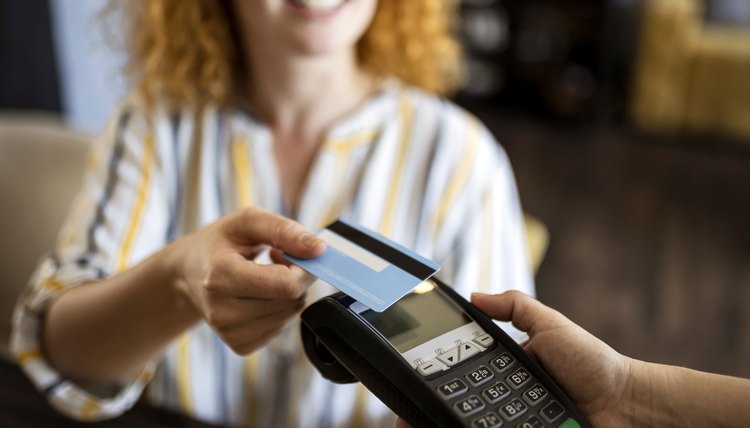 Mujer joven pagando con una tarjeta de crédito en un café.