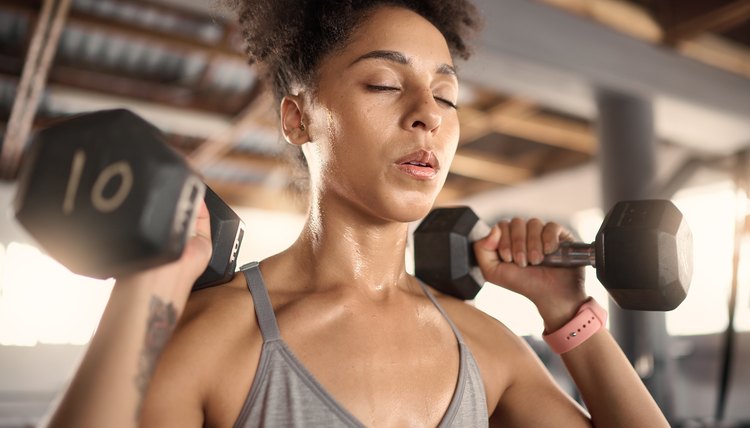 Fitness, exercise and dumbbell with a black woman athlete training in a gym for strong health or wellness. Sports, motivation and workout with a female bodybuilder in a sports club for a workout