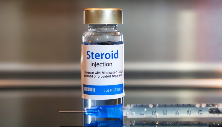 Bottle of Steroid injection with a syringe on black table and stainless steel background.