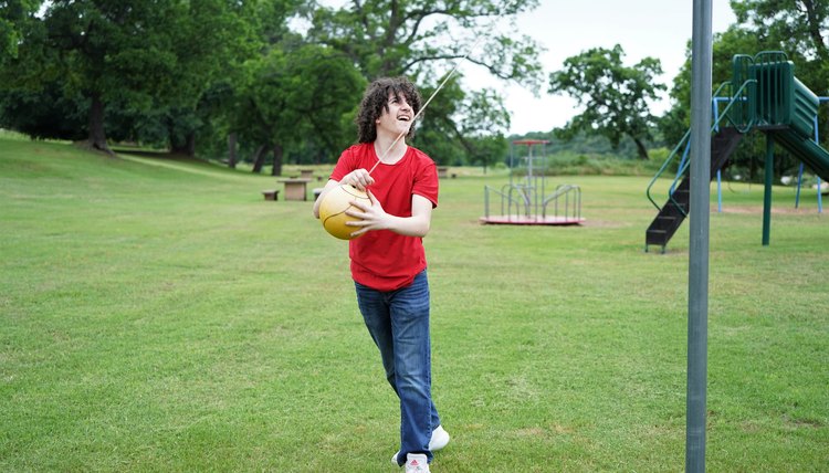 Teen Boy Plays Tether Ball on Playground