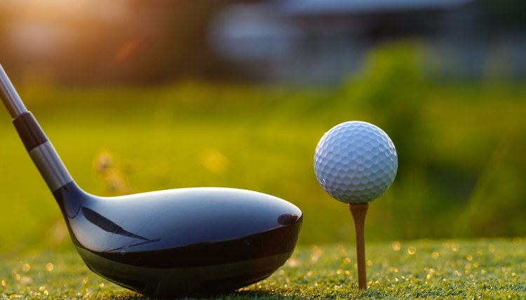 Golf clubs and golf balls on a green lawn in a beautiful golf course.