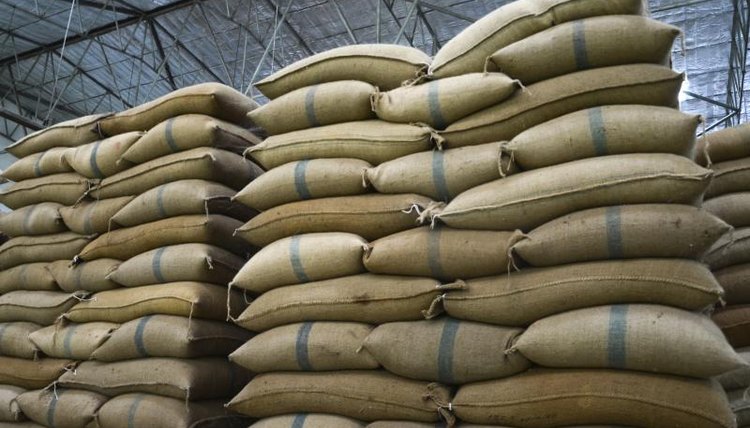 A tall stack of bags of rice in a warehouse