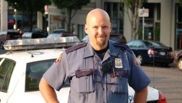 A police officer stands behind a police car.