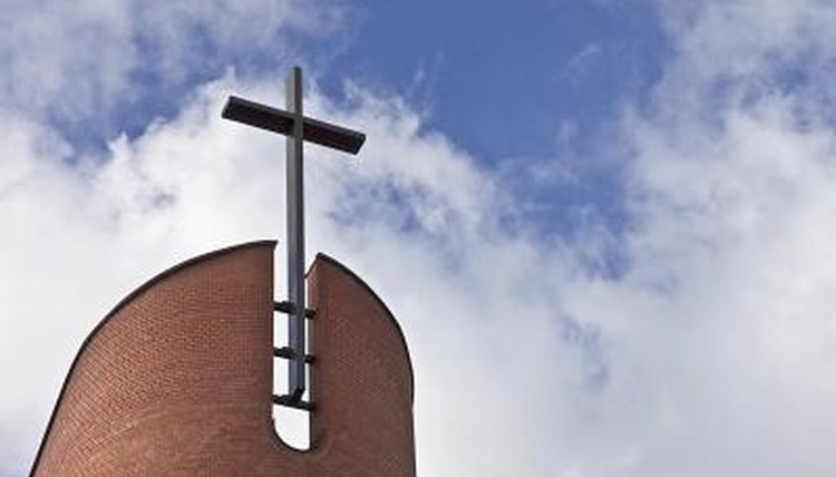 Cross on church roof against sky with clouds