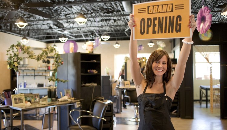 An excited salon owner holds up an open sign.