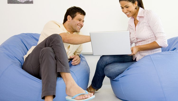 Businesspeople sitting in bean bag chairs and looking at laptop