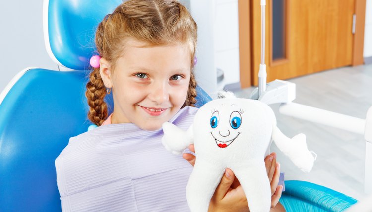Cheerful child holding a toy tooth