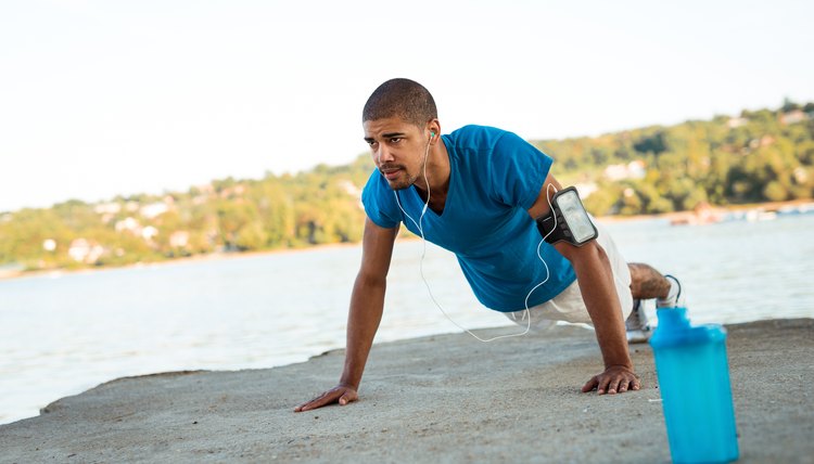 Young male athlete doing push ups next to the river.