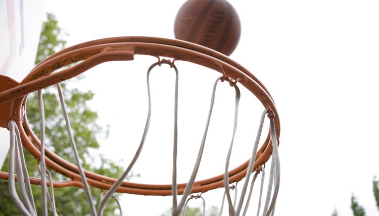 Basketball falling toward hoop on tree-shaded court
